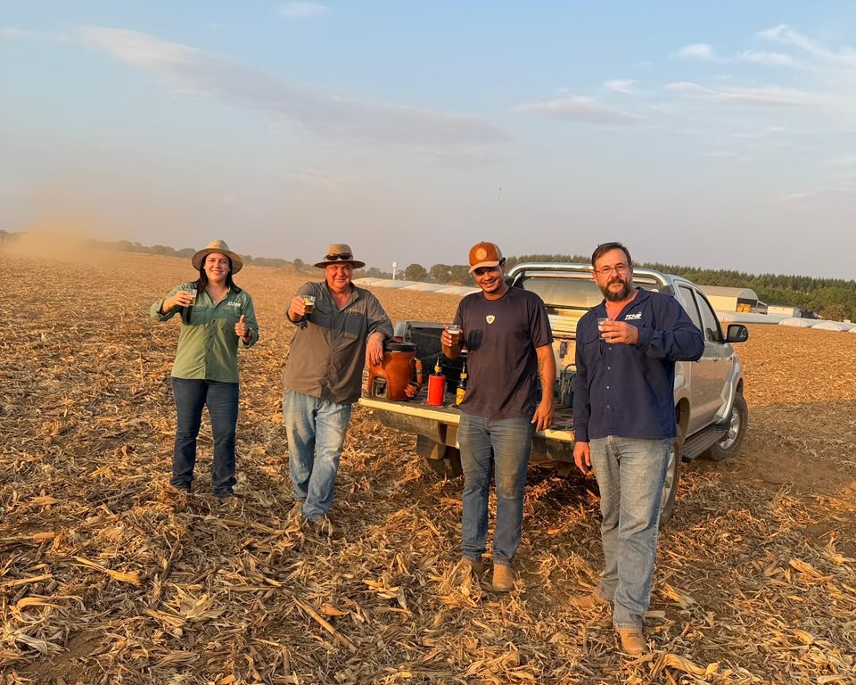 Quatro pessoas em uma área agrícola, próximas a uma caminhonete.